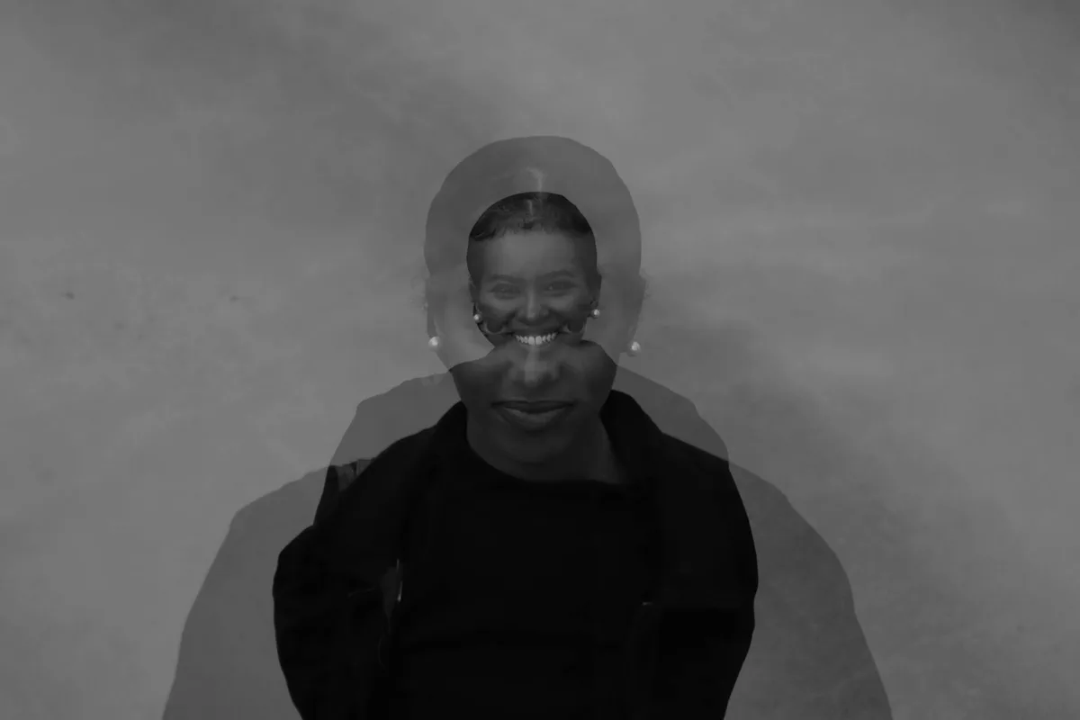 Künstlerisches Schwarz-Weiß-Doppelbelichtungsporträt einer lächelnden Frau mit surrealem Effekt