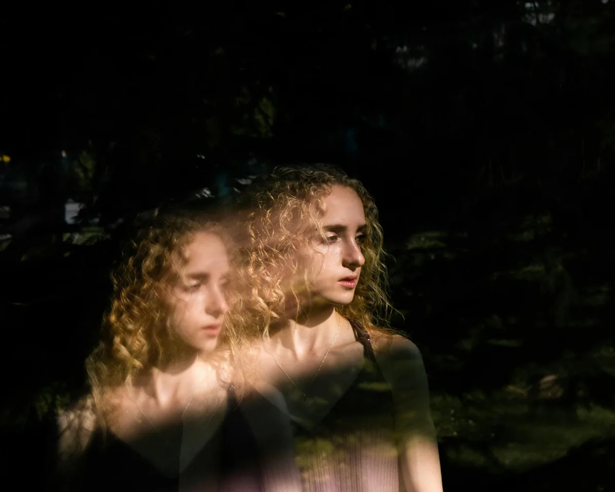 Artistic portrait of a young woman with a reflective double exposure effect.