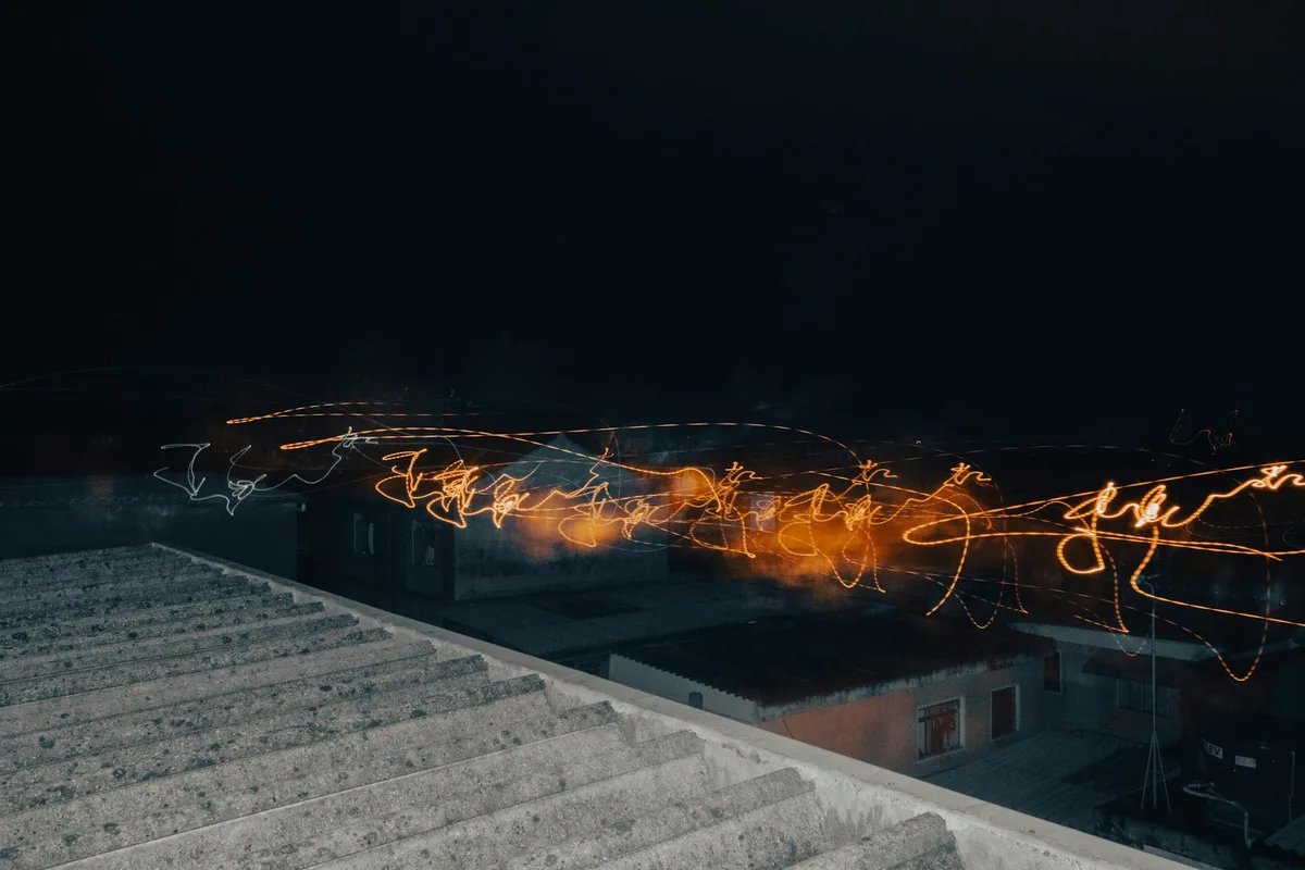 Scie luminose in lunga esposizione sopra tetti notturni