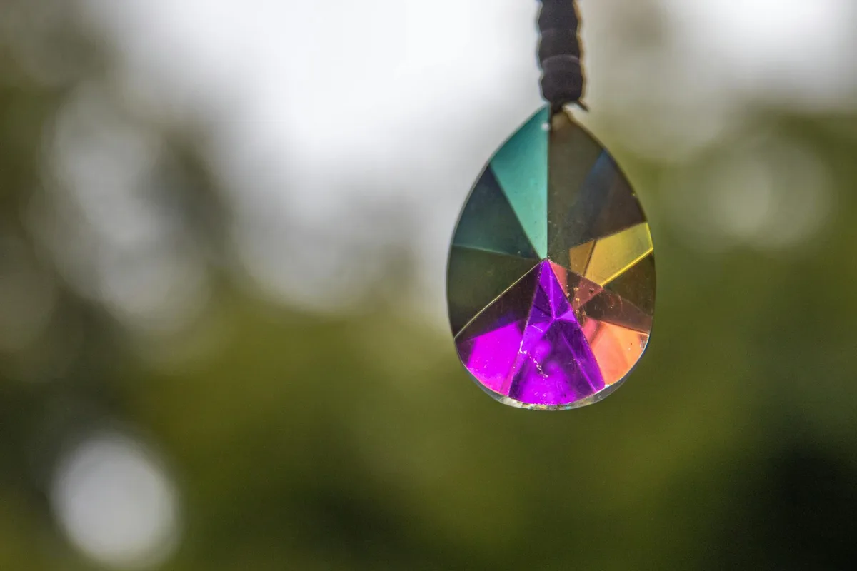 Nahaufnahme eines bunten Kristallprismas mit Regenbogenreflexionen im Freien