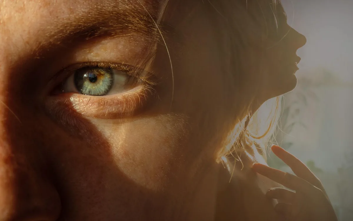 Primo piano di occhio azzurro e silhouette femminile in doppia esposizione.