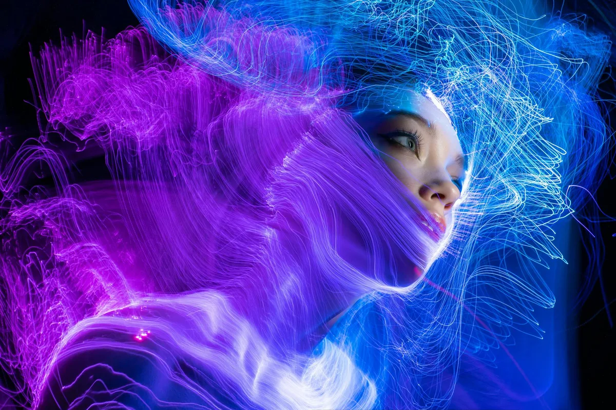 Ritratto dinamico di donna avvolta da scie luminose al neon viola e blu