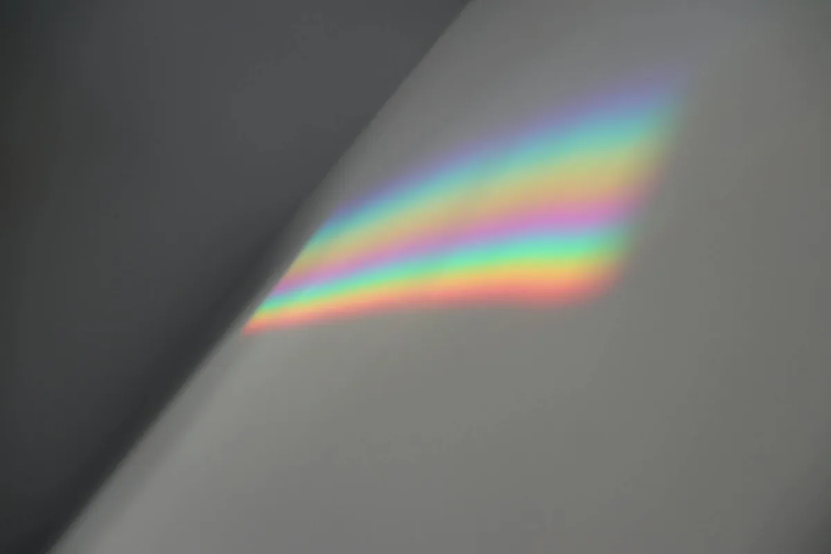 Sanftes Regenbogen-Lichtspektrum auf einer grauen Innenwand