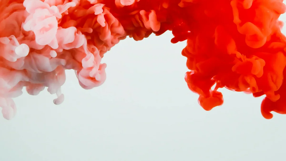 Abstrakte Komposition aus roter und rosa Tinte, die frei im Wasser wirbelt