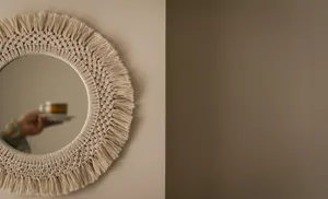 A decorative mirror reflecting a person's hand holding a coffee cup indoors.