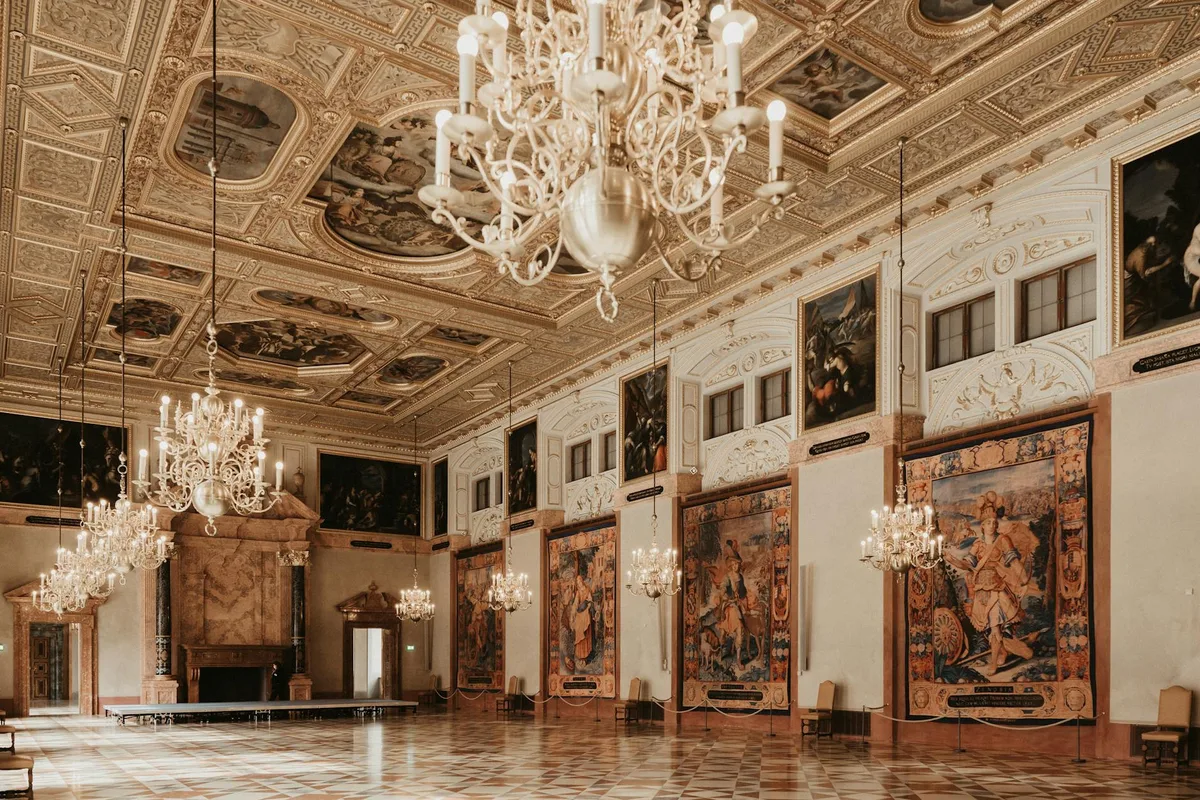 Grande salone interno con lampadari ornamentali e dipinti storici, lusso ed eleganza.