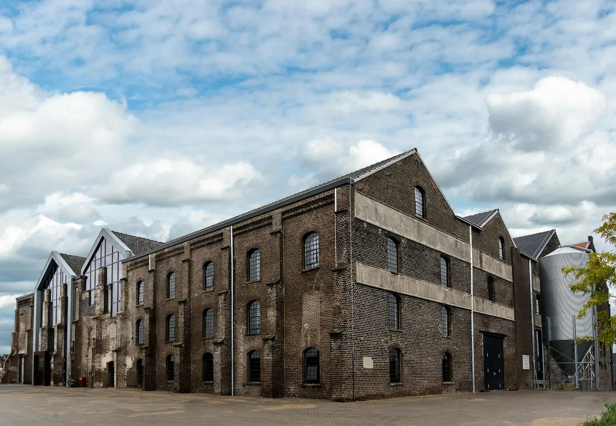 Edificio storico in mattoni di un magazzino sotto cielo azzurro con nuvole, dettagli architettonici.