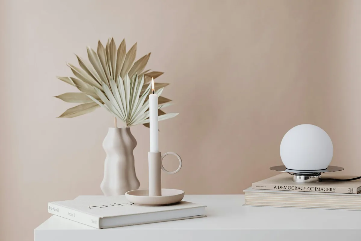 Setup minimalista con candela, libri e decorazioni moderne per la casa