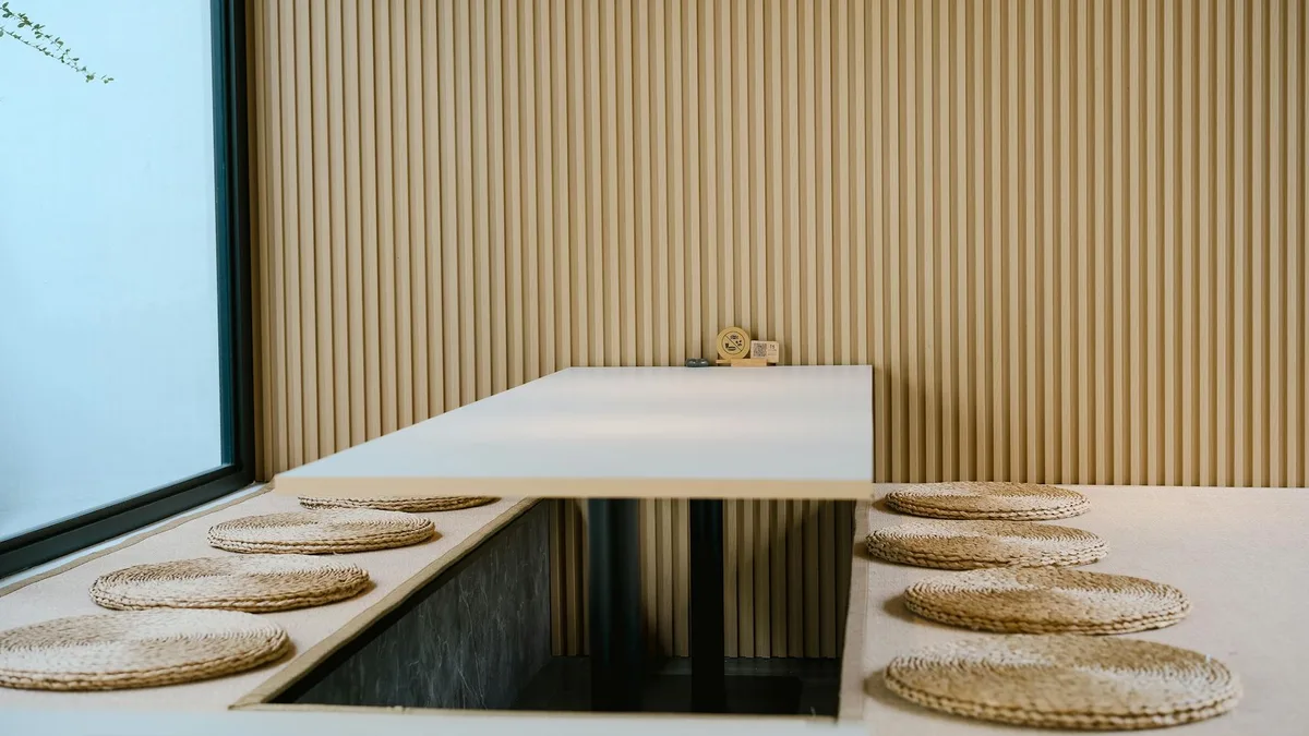 Zona pranzo moderna e minimalista in stile giapponese con toni beige e stuoie intrecciate