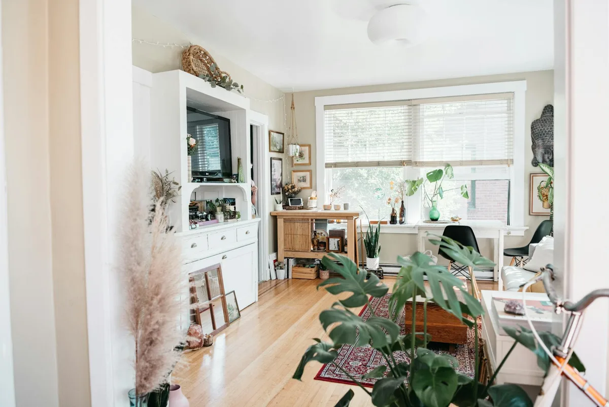 A well-decorated living room featuring natural light, various indoor plants, and elegant furniture.