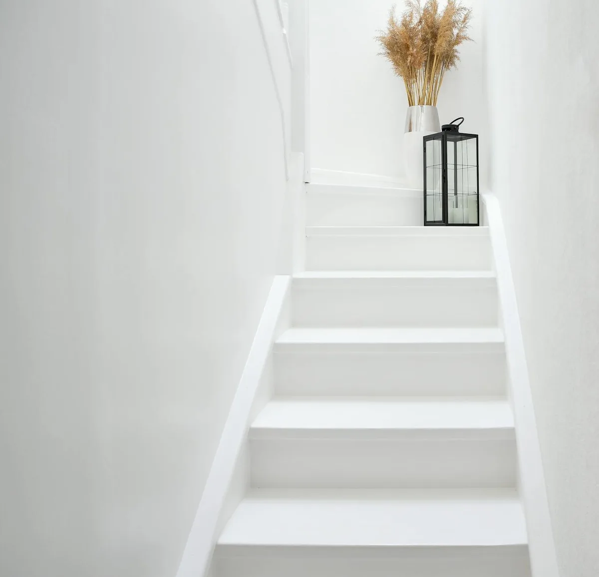 Helle, moderne skandinavische Treppe mit Glaskugellampe und Trockenpflanzen