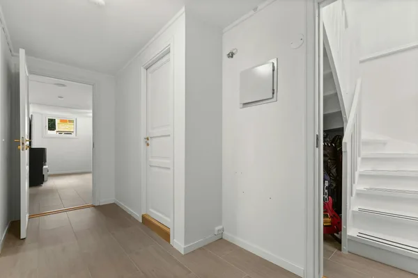 Heller, moderner weißer Flur mit Treppe und offenen Türen