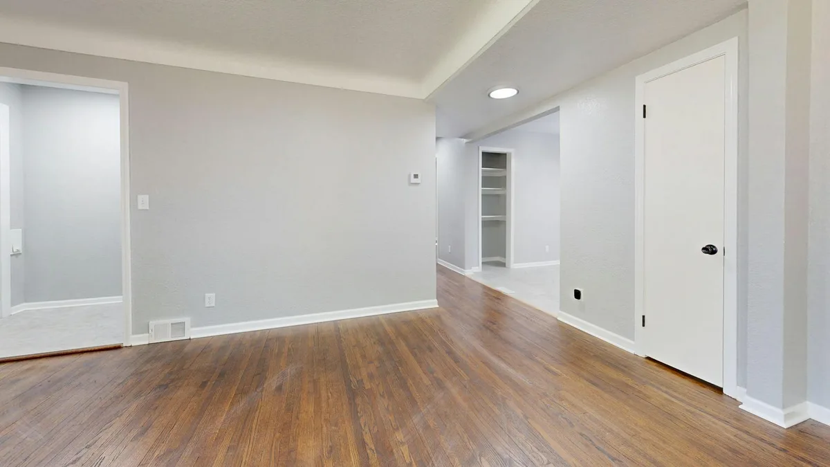 Stanza vuota e luminosa con pavimento in legno per annunci immobiliari