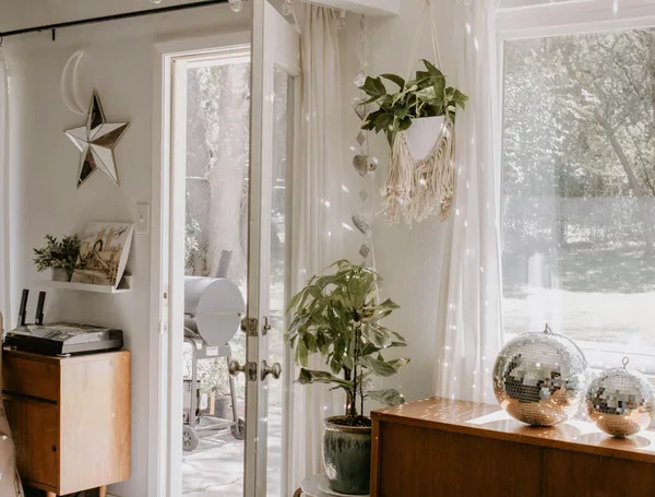 Bright interior space featuring houseplants, sunlight through glass doors, and sparkling decor elements.