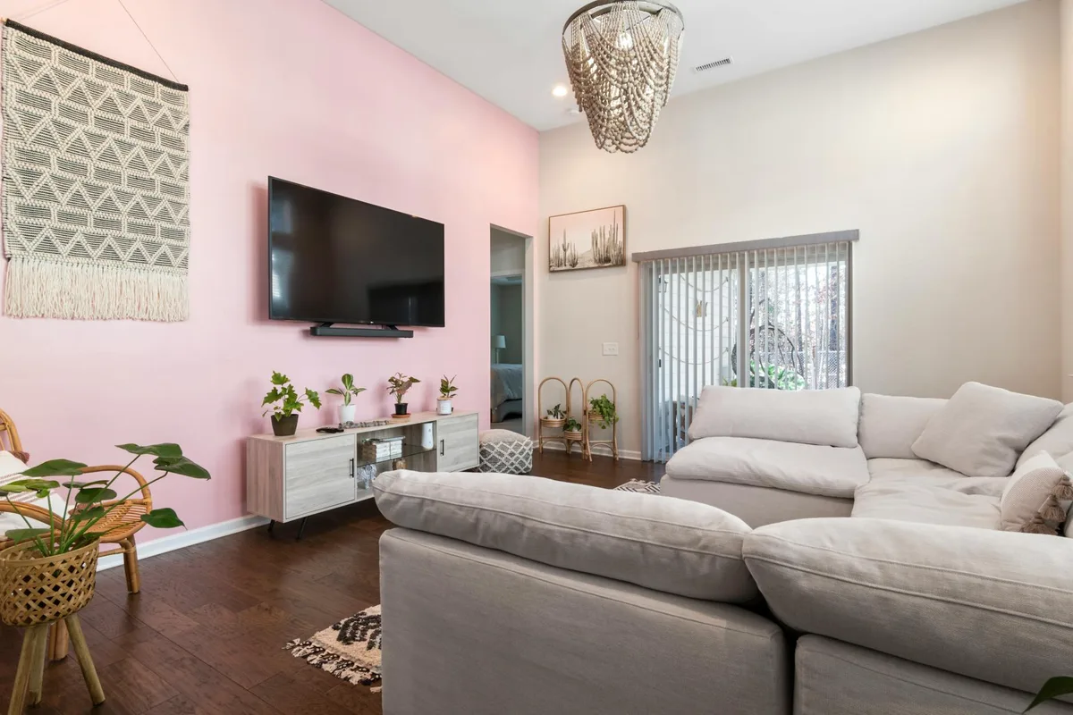 Salotto chic con parete rosa, divano comodo e arredi contemporanei