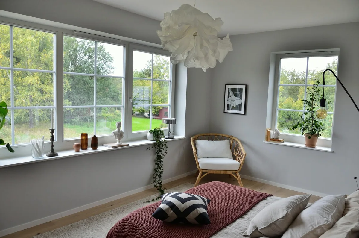 Chambre scandinave cosy avec lumière naturelle, grandes fenêtres et verdure