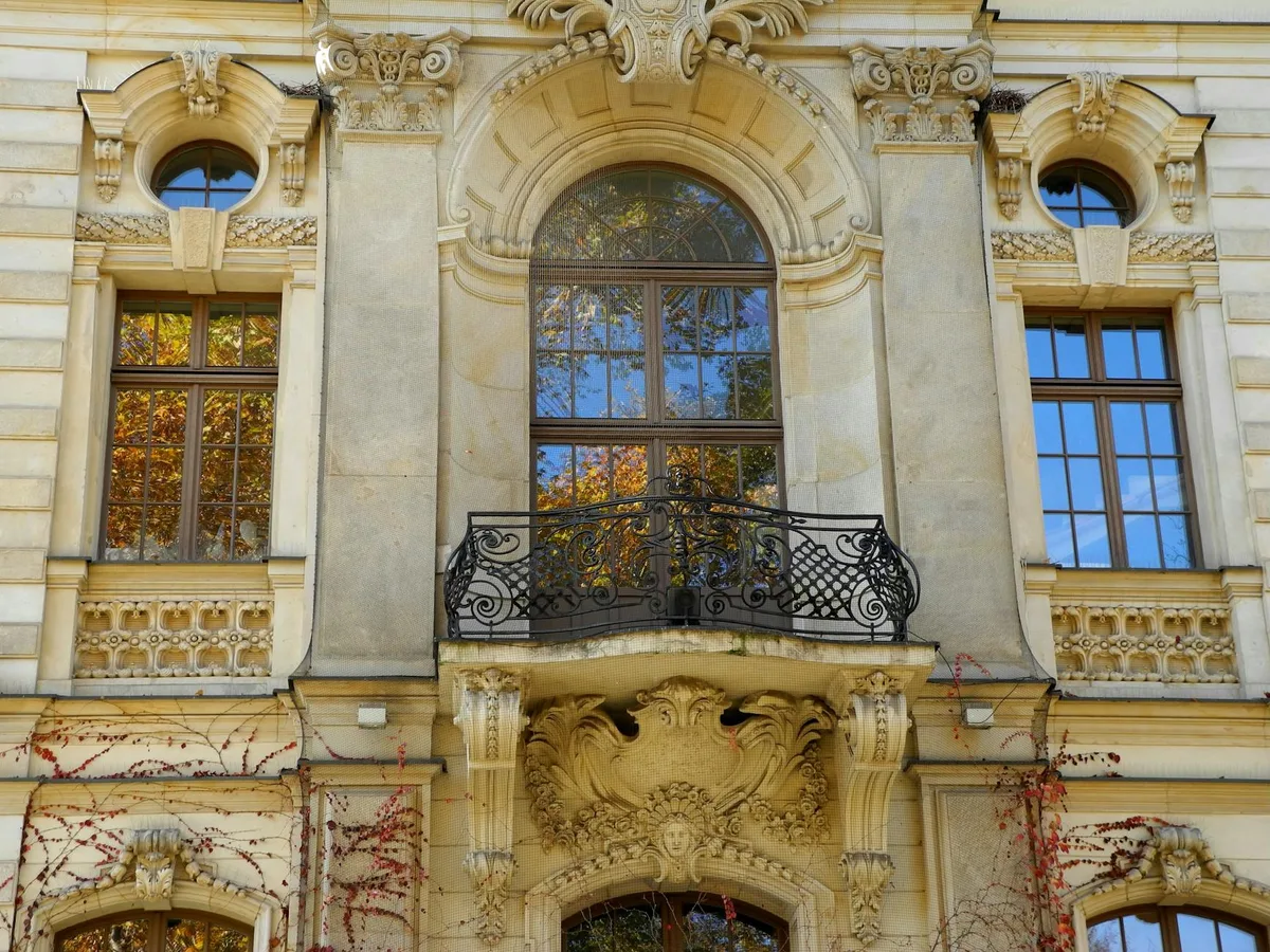 Facciata dettagliata di edificio storico con finestre ornate e riflessi autunnali all'aperto