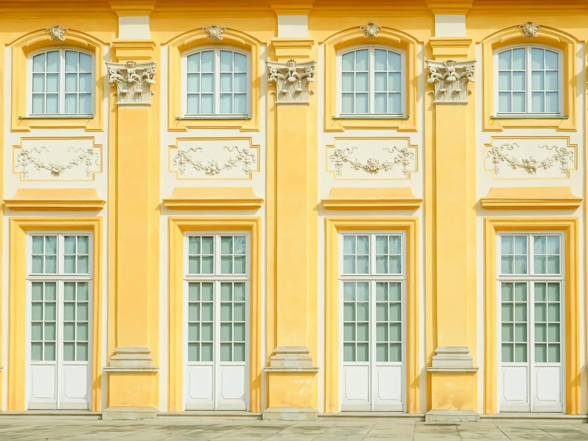 Image détaillée d'une façade baroque européenne jaune aux fenêtres symétriques