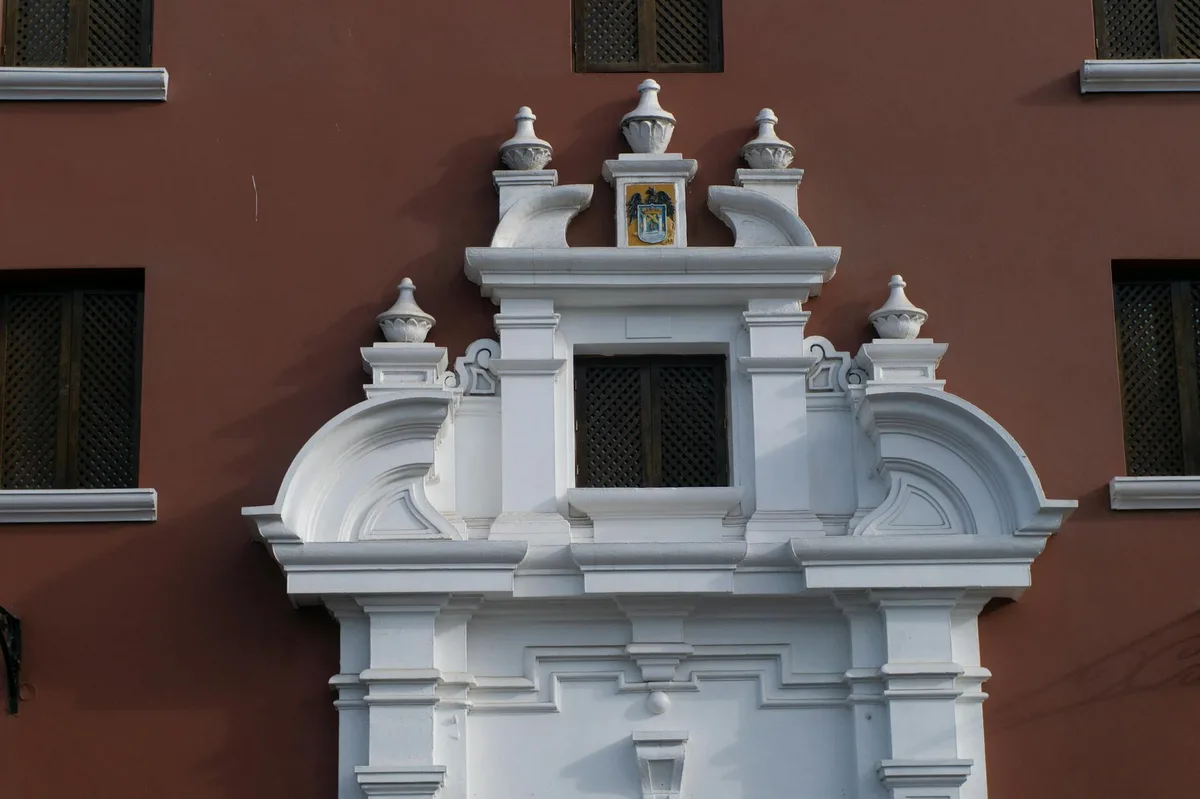 Dettaglio di una facciata barocca bianca su muro rosso con elementi architettonici