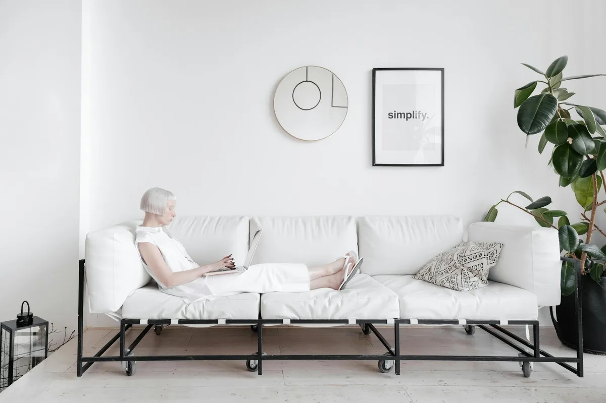 Ältere Frau entspannt auf moderner weißer Couch im minimalistischen Design