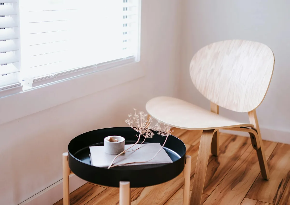 Stanza elegante in stile Japandi con sedia in legno, tavolo rotondo e oggetti decorativi