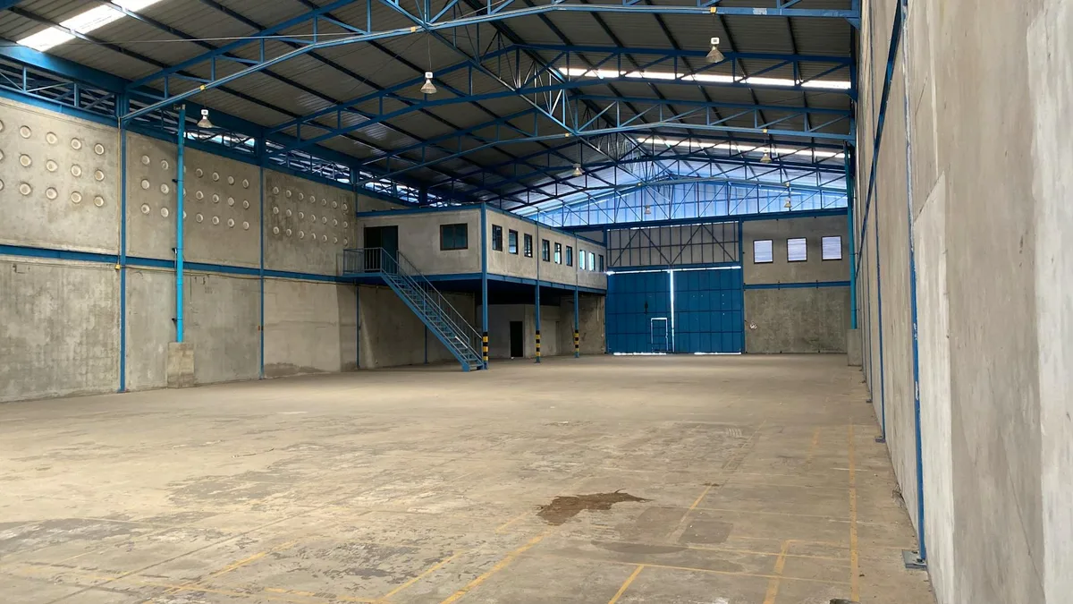 Magazzino vuoto con struttura in acciaio blu e pareti in cemento a Bangkok