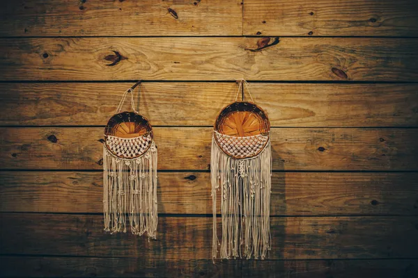 Handmade macrame and wicker baskets on warm wooden wall, perfect for rustic decor.
