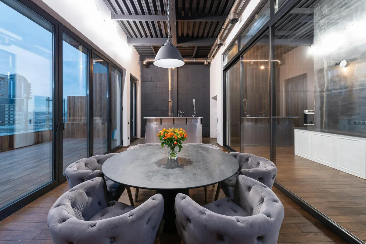 저녁 시간 파노라마 윈도우 옆 라운드 테이블과 암체어가 있는 모던 라운지 인테리어