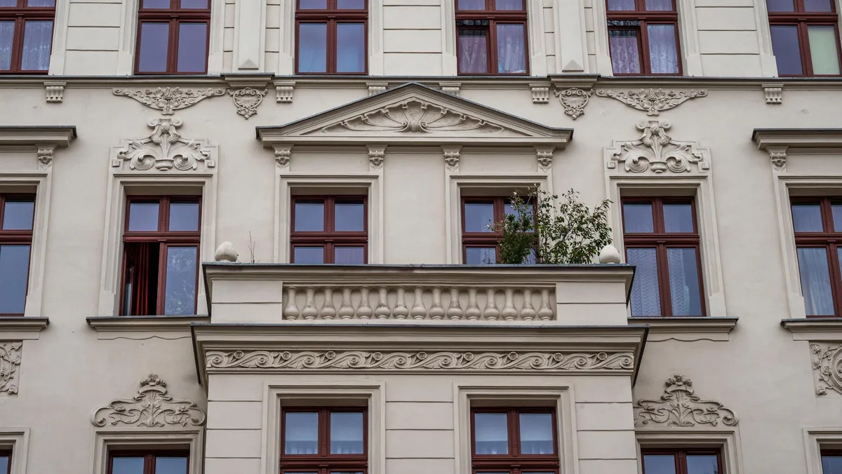 Ornamentale europäische Gebäudefassade mit detaillierten Steinmetzarbeiten und roten Fensterrahmen