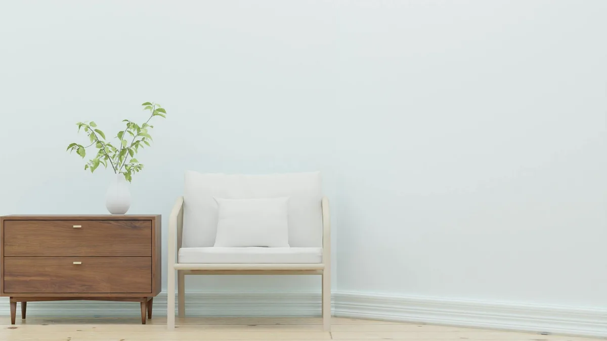 Elegantes minimalistisches Wohnzimmer mit weißem Sessel und hölzernem Beistelltisch mit Pflanze