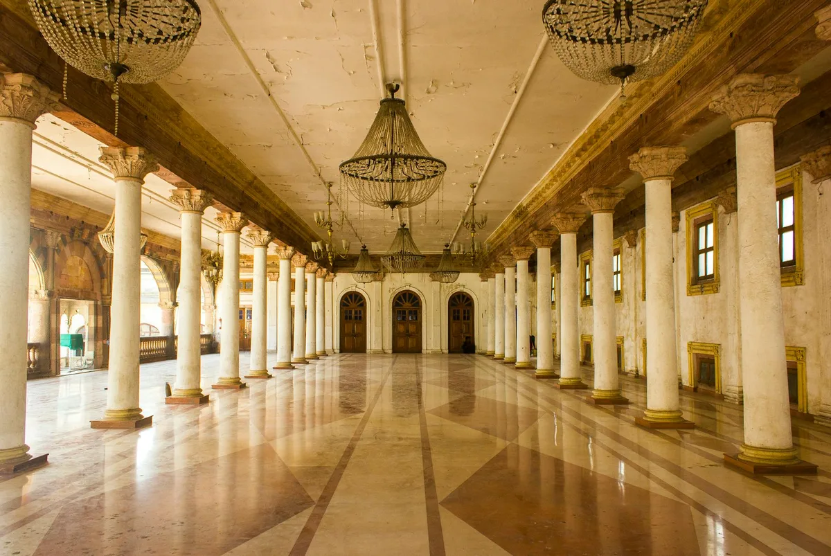 Sala spaziosa con colonne e lampadari al Rajwada Palace, sito storico a Indore, India