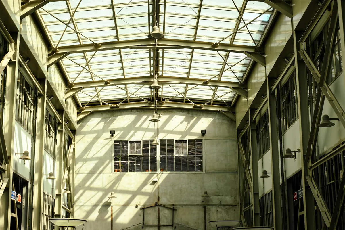 Interno industriale spazioso con tetto in vetro e luce naturale che inonda lo spazio
