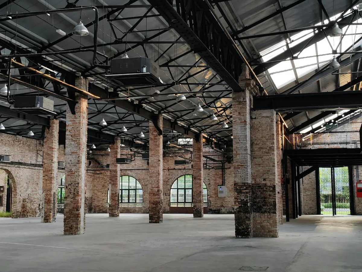 Magazzino industriale spazioso con mattoni a vista e struttura in acciaio illuminato da luce naturale