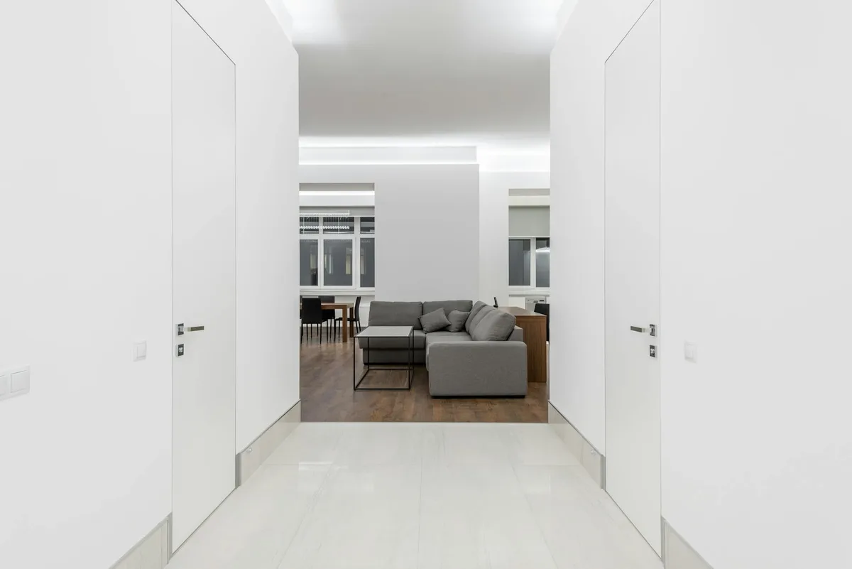 Geräumiges minimalistisches Wohnzimmer mit grauem Sofa und weißen Wänden