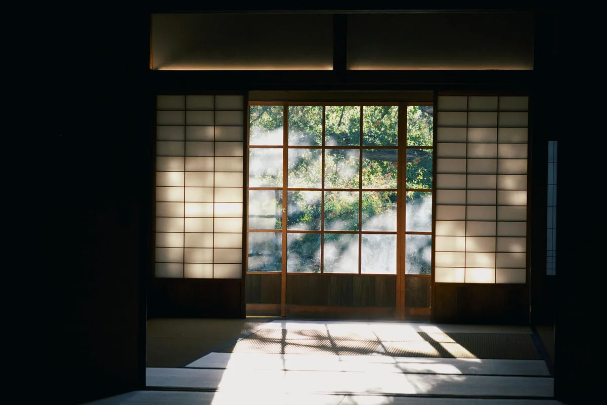 Pièce japonaise paisible avec shoji traditionnels, lumière diffusée et vue sur la nature