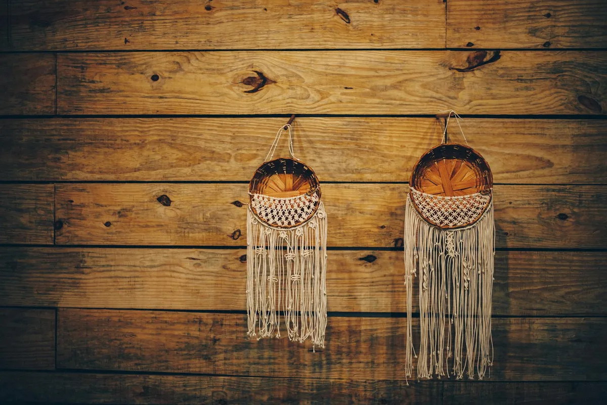 Due cesti intrecciati con frange appesi a una parete rustica in legno, tocco artigianale
