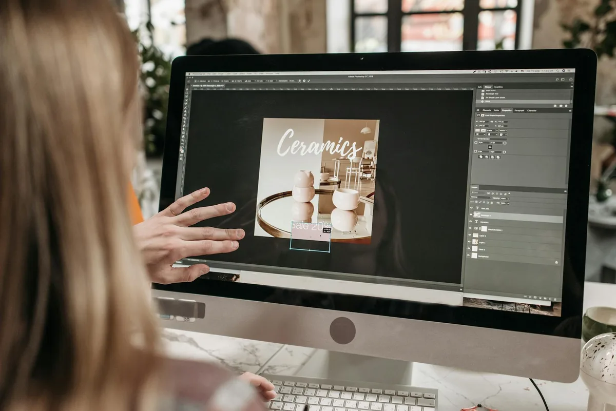 Designer grafico al lavoro su promozione ceramiche con Adobe Photoshop su iMac