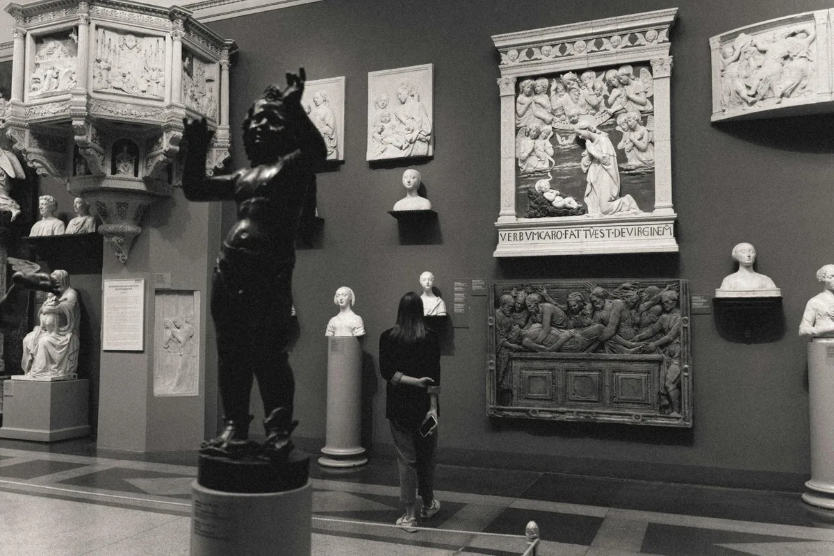 Foto in bianco e nero di museo con sculture classiche e visitatore