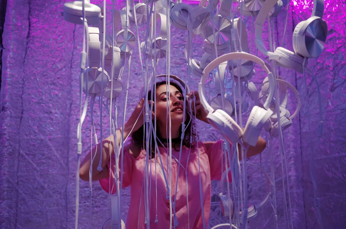 Femme écoutant de la musique sous une installation violette de casques