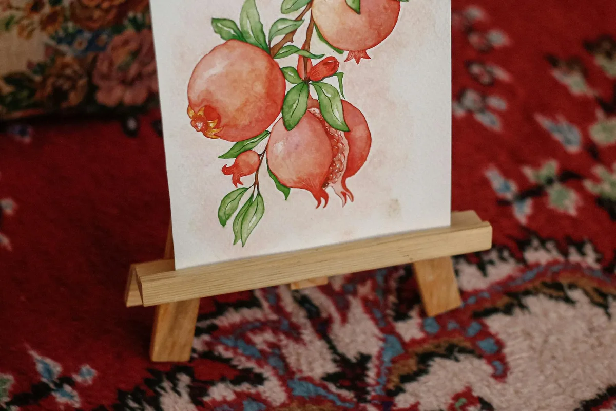 Aquarelle artistique de grenades sur chevalet en bois et tapis à motifs