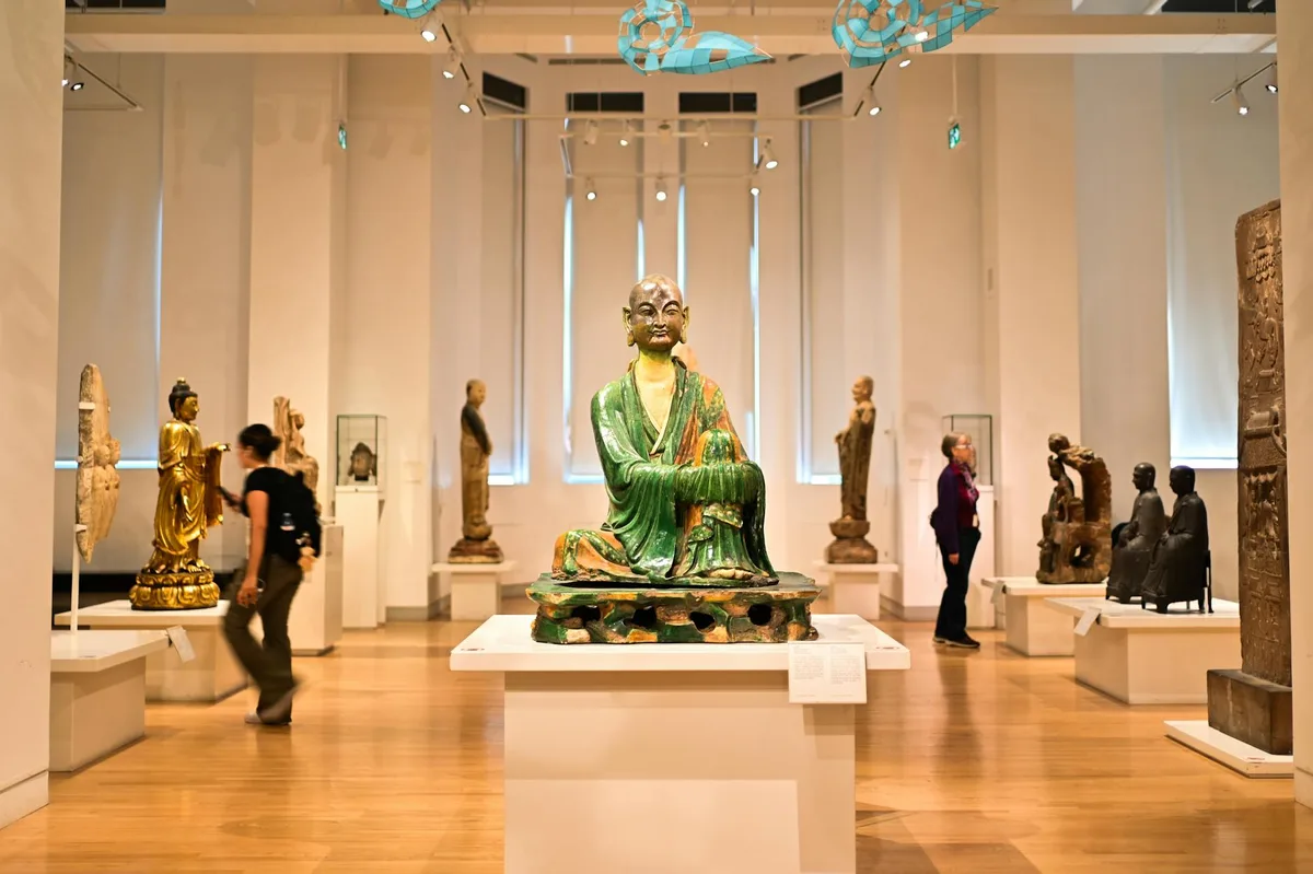 Statue di Buddha in mostra al museo con visitatori che osservano
