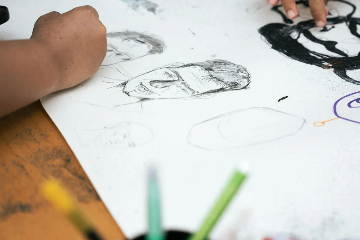 Nahaufnahme von Händen, die Bleistiftskizzen mit Buntstiften zeichnen