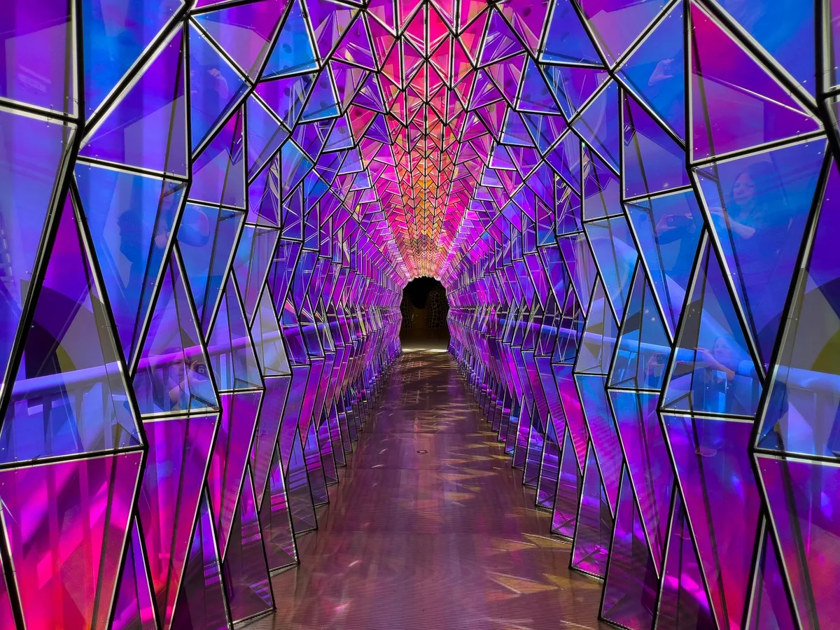 Tunnel geometrico ipnotico illuminato da vivaci tonalità viola e blu