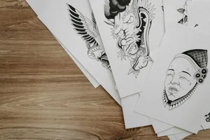 Top view of detailed black and white drawings on paper arranged on a wooden table.