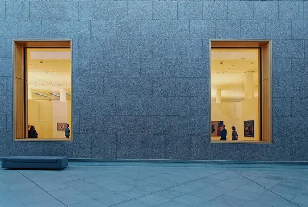 Esterno di galleria d'arte moderna con grandi vetrate che incorniciano una mostra