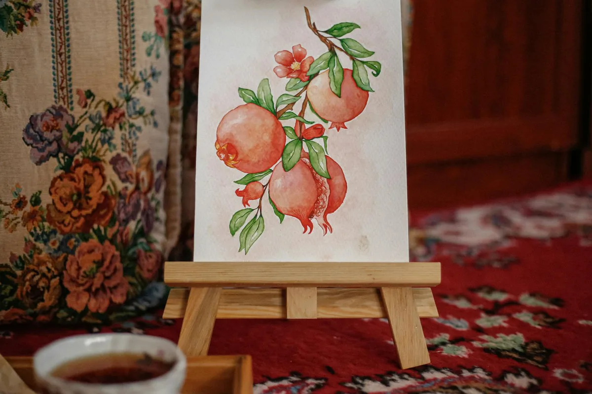 Aquarela de romãs em cavalete de madeira em ambiente interno aconchegante