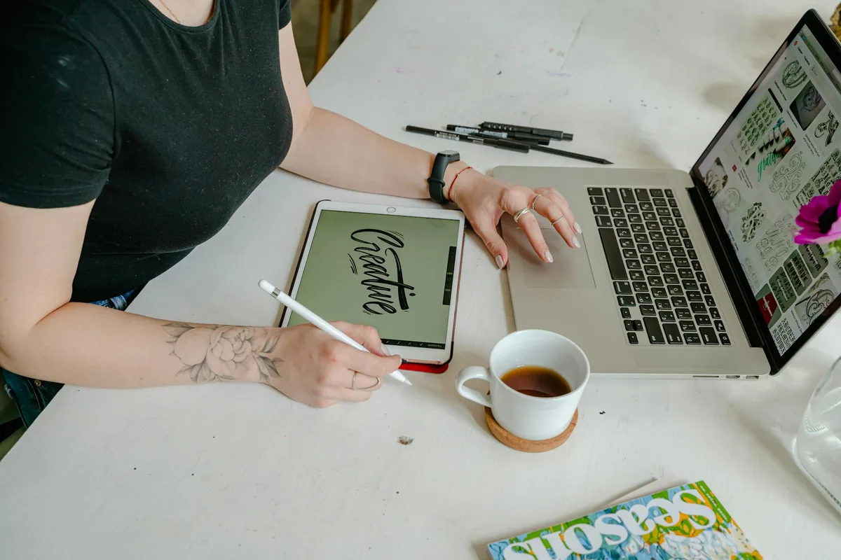 Donna che lavora al design digitale con tablet e laptop in un ufficio creativo