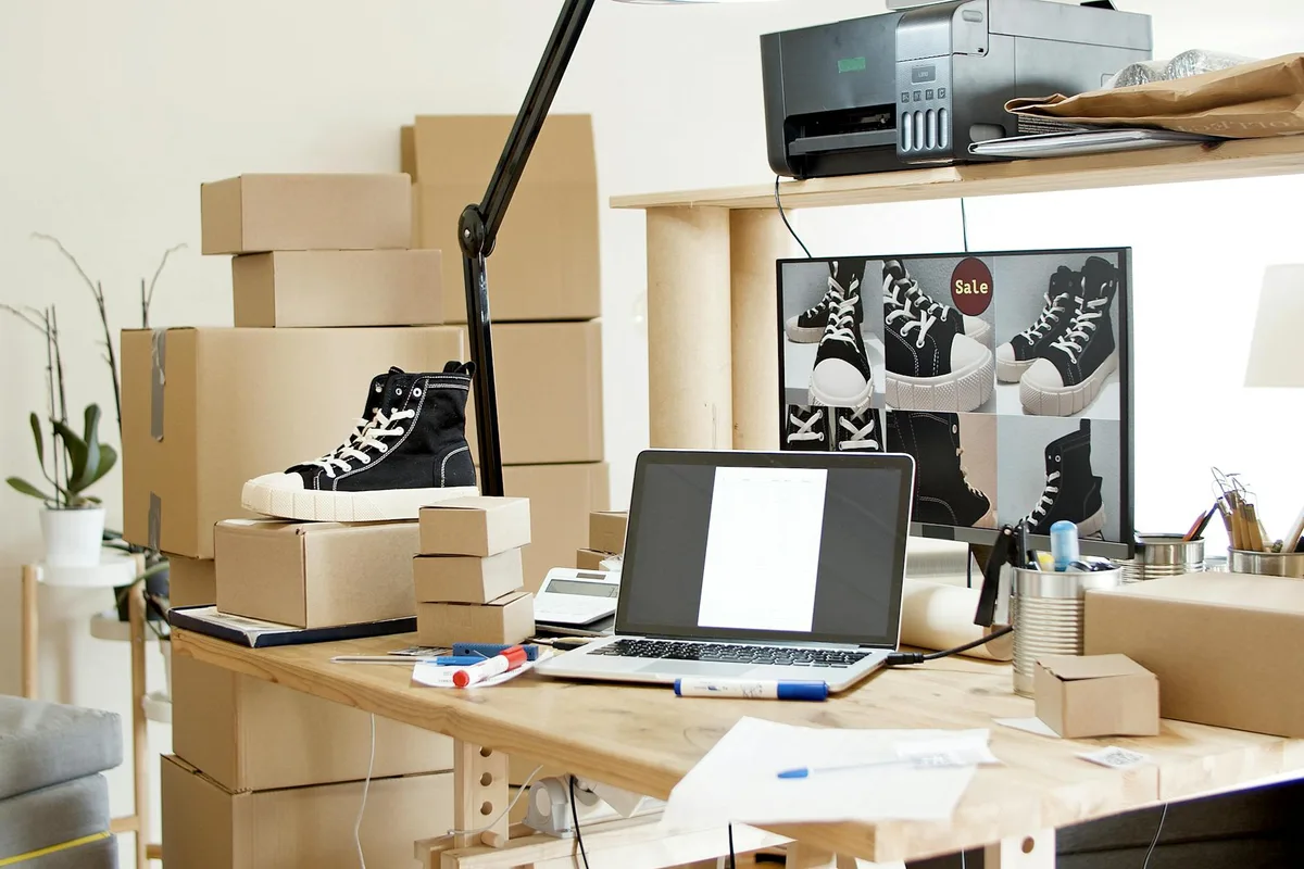 Espacio de trabajo activo con zapatillas, cajas y portátil indicando tienda online