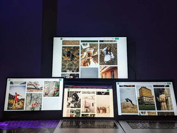 Espace de travail high-tech avec trois laptops et un moniteur affichant des images