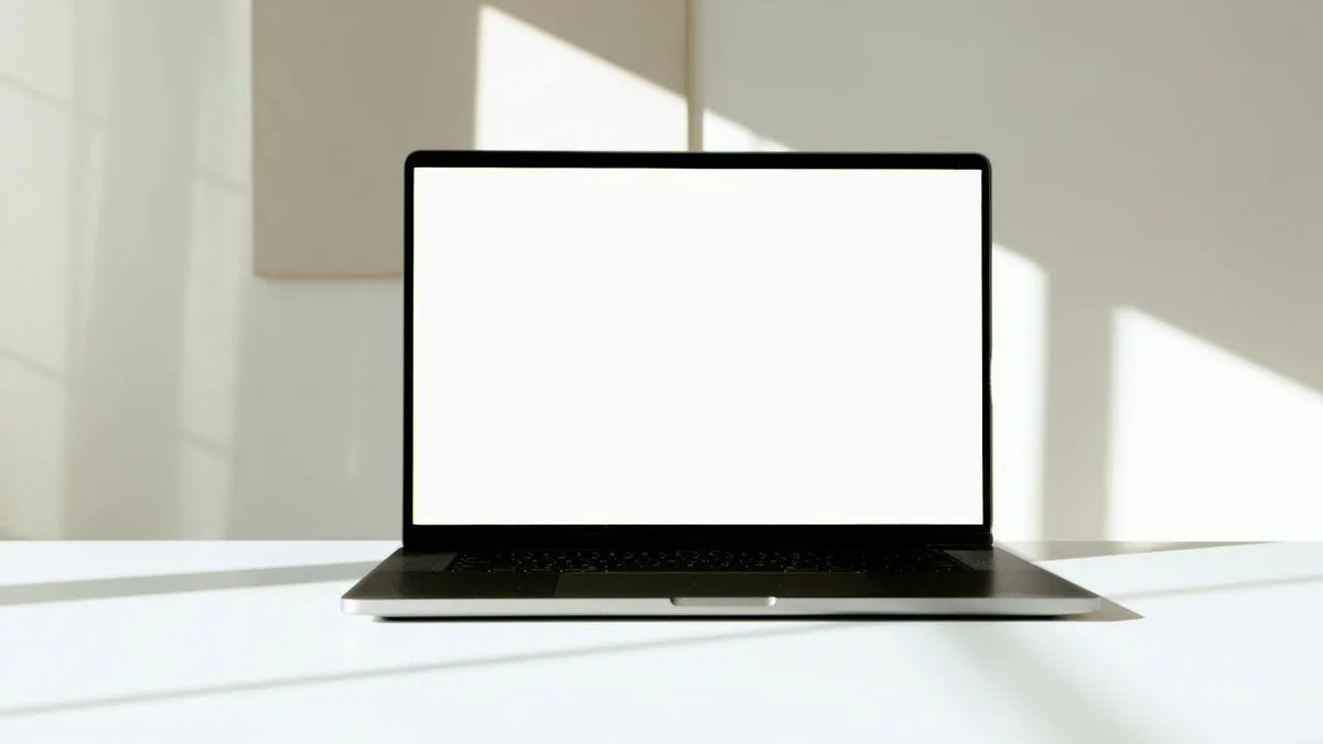 Laptop con schermo bianco su scrivania illuminato dalla luce solare